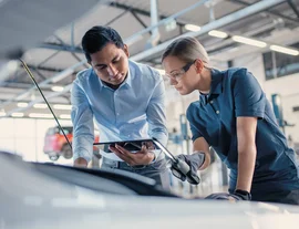 A man and woman asessor or engineer looking into a car engine - listing