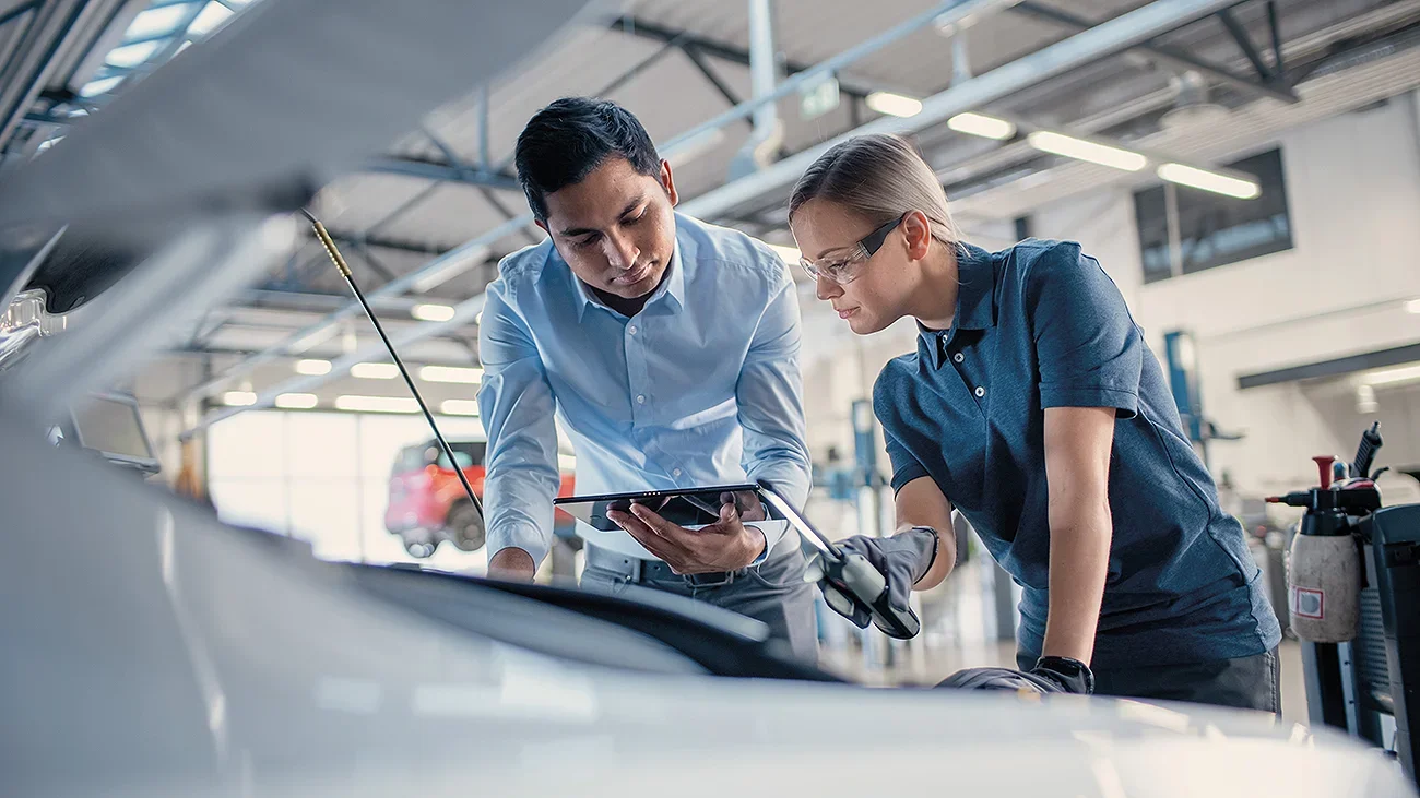 A man and woman asessor or engineer looking into a car engine