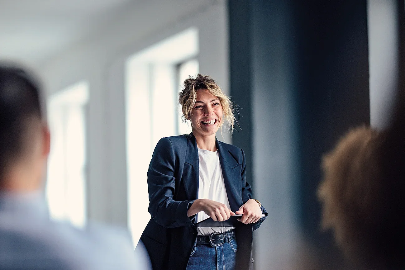 A woman smiling with a clipboard in front of others