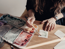 A woman with a paint brush and a paint board listing.png