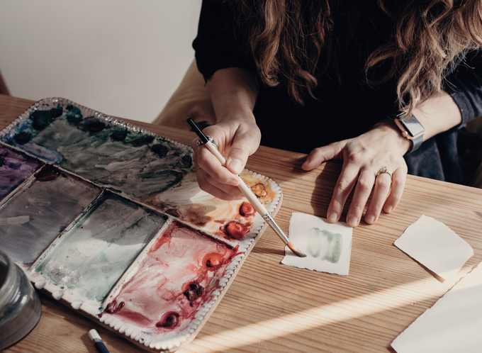 A woman with a paint brush and a paint board listing.png