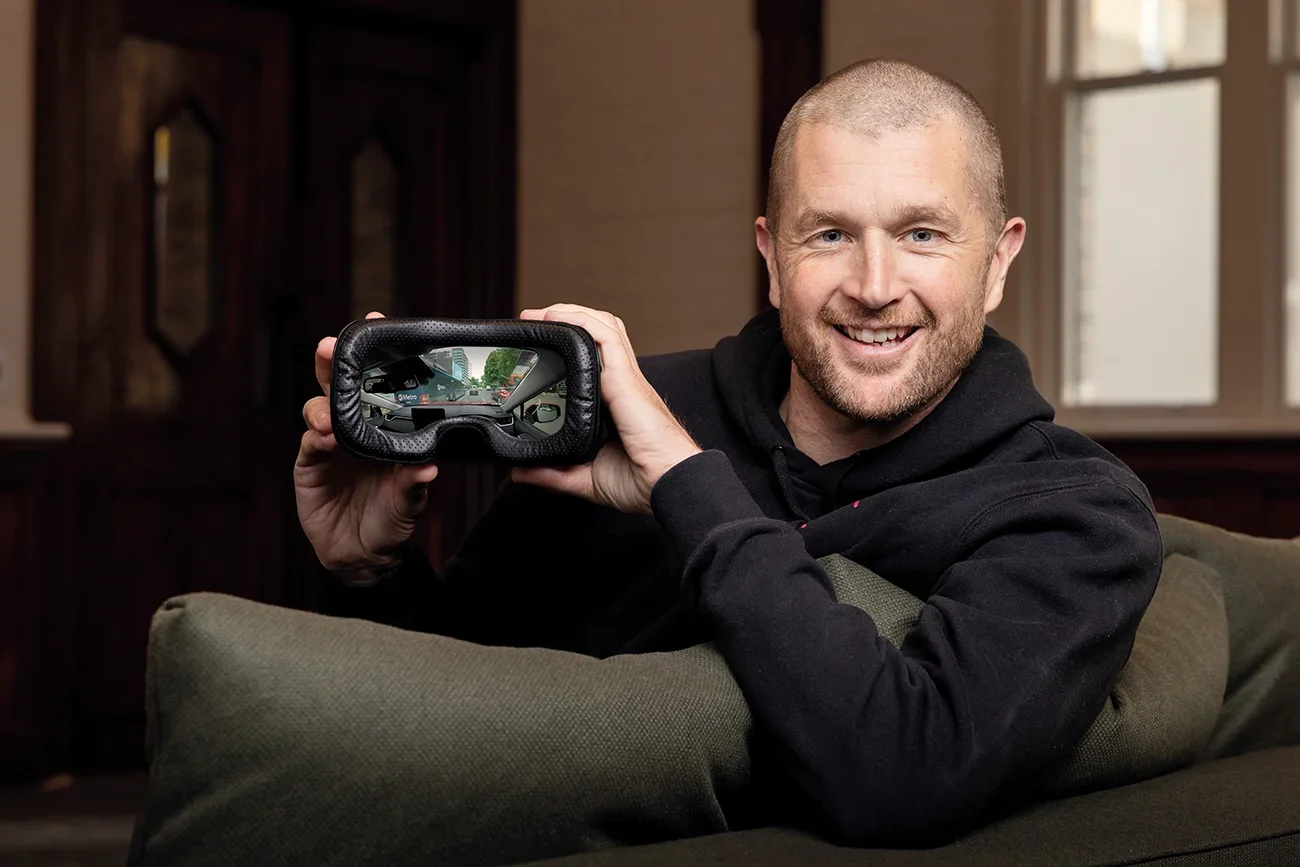 Adam Hutchinson holding a VR headset on a couch