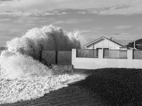 An ocean wave hitting a beachside home