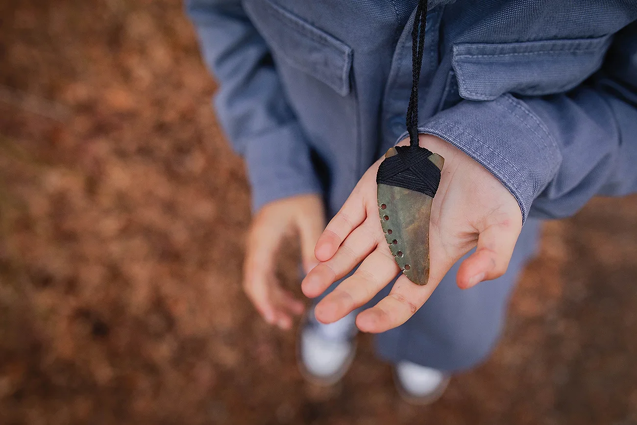 Someone holding a pounamu necklace in their hand