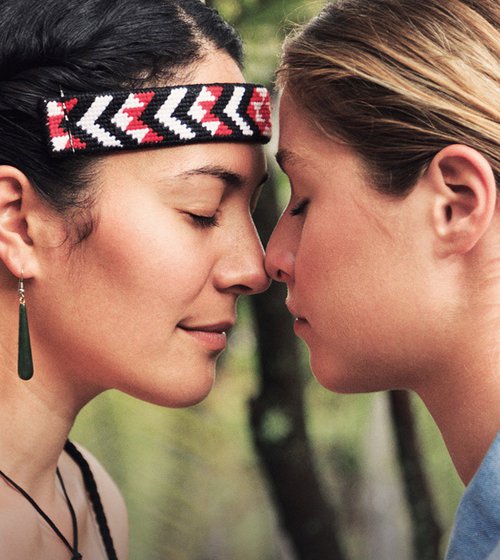 Two people press their noses together in a traditional Maori hongi greeting