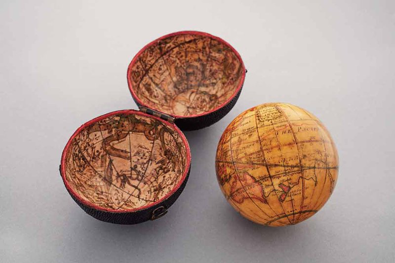 Two antique pocket globes depicted on grey surface