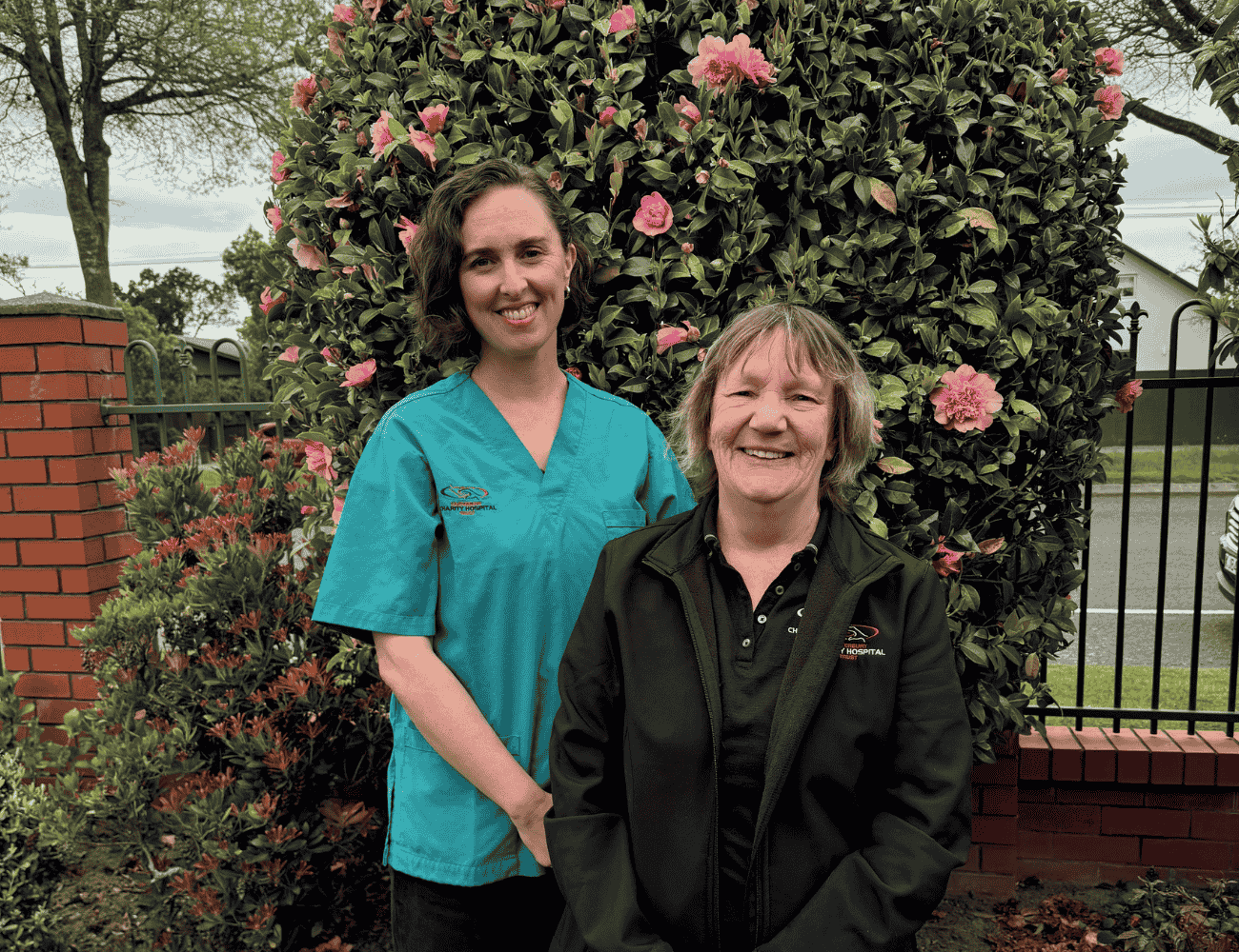 Two woman smiling at the camera in a park