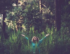 Woman-happily-raising-her-arms-in-the-middle-of-a-forest.jpg