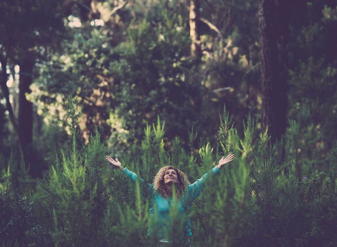 Woman-happily-raising-her-arms-in-the-middle-of-a-forest.jpg