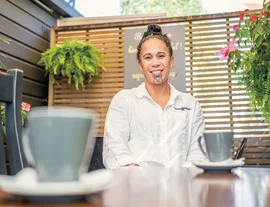 Woman at a table in a cafe - Aroha for the reo - listing