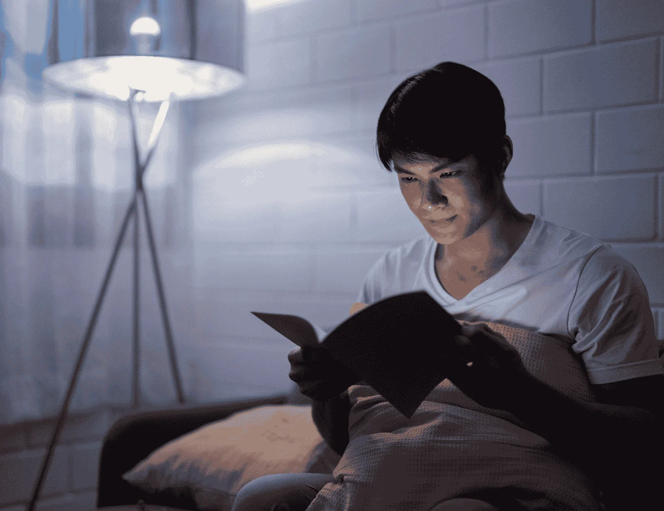 Young boy reading in bed in a darkened room