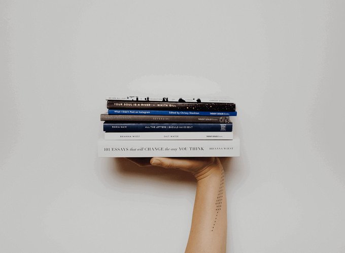 Hand holding up a stack of books