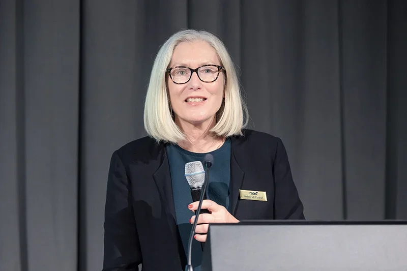 Helen McDowall with a microphone at a podium