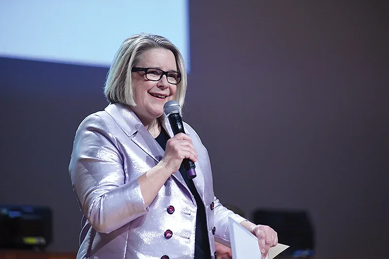 MAS CEO Suzanne Wolton with a microphone at a podium