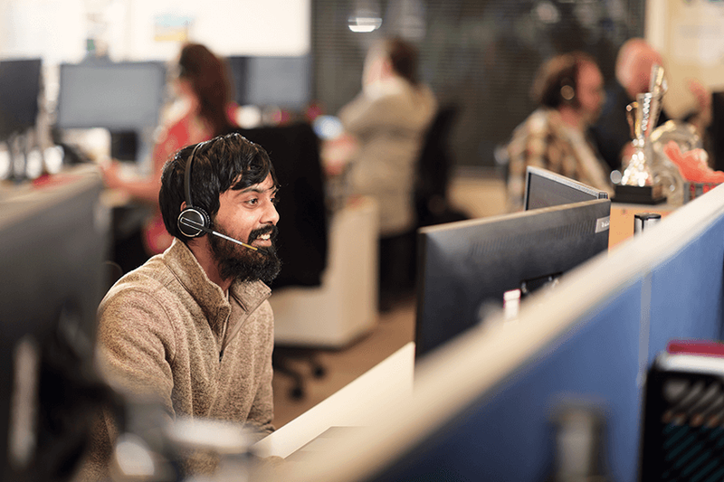 smiling call centre operator on a call at his desk