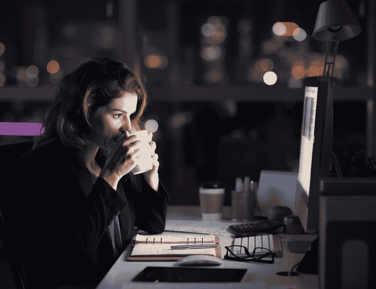 woman working late at night sipping a hot drink