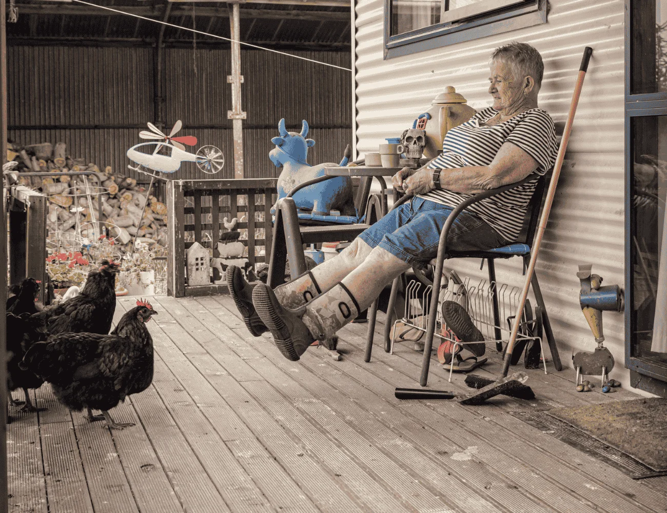 young woman sitting on a chair on a porch with her chickens