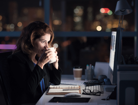 young woman working late at night drinking a hot drink listing